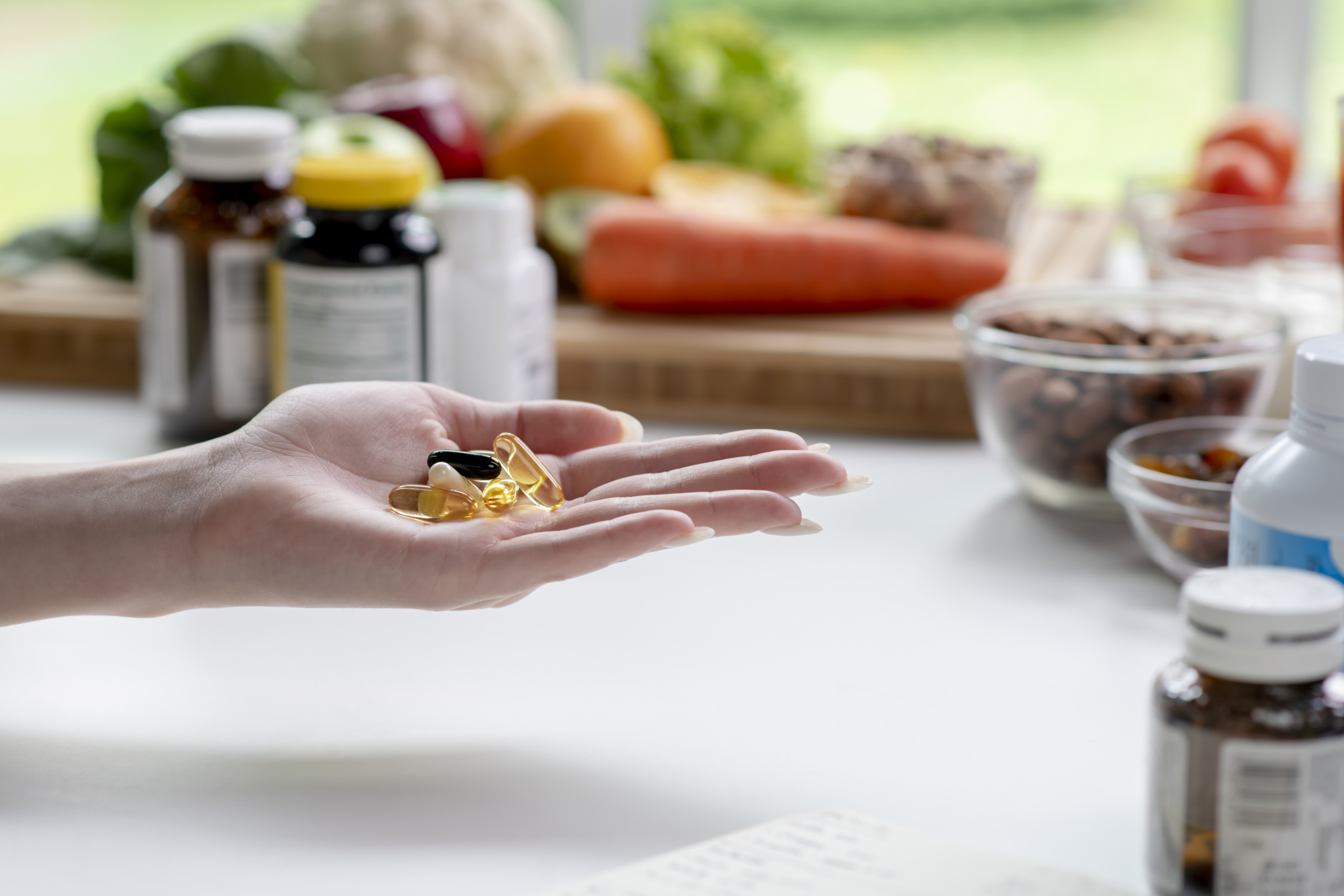 consultoria-complemetos-alimenticios Woman professional nutritionist checking dietary supplements in hand, surrounded by a variety of fruits, nuts, vegetables, and dietary supplements on the table